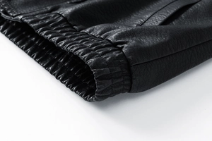 Detailaufnahme der schwarzen PU-Lederstruktur mit elastischen Rippbündchen und Nähten