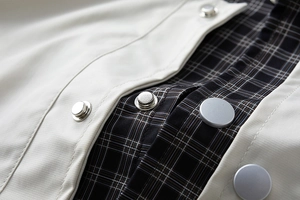 Detail of matte silver metal snaps and plaid lining on a beige twill jacket