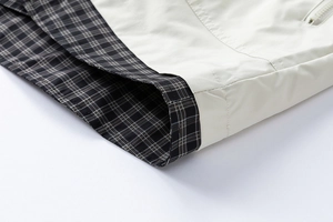 Detail view showing stitching and grey plaid lining of the cream cargo jacket cuff