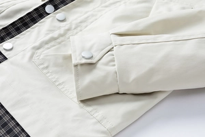 Detail view of khaki work jacket featuring metal buttons and classic plaid lining texture