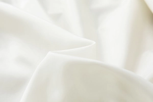 Detail view of smooth white fabric texture with high luster and elegant drape quality