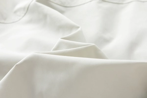 Close-up of high-quality white textile fabric with precise stitching and fine texture