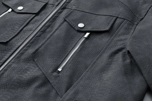 Close-up van zwart leren jack met slangenpatroon textuur en zilveren metalen drukknopen