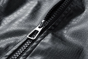 Detail of black crocodile texture leather with silver metal zipper and sleek puller