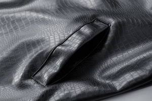 Close-up of black crocodile-embossed leather jacket featuring a side pocket detail