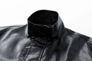 Close-up of black leather jacket stand collar with matte metal snaps and fine stitching