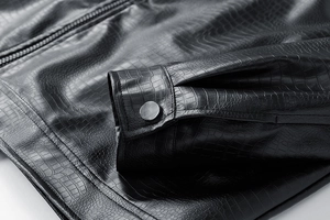 Close-up of black crocodile embossed leather jacket featuring silver snap buttons and zipper
