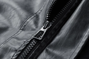 Detailed close-up of heavy-duty metal zipper on black textured faux leather jacket