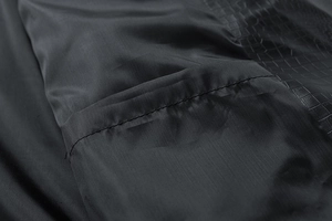 Detail of black lapel jacket showing crocodile-embossed leather and smooth fabric seams