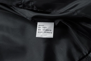 Detail view of garment care label showing 100% polyester lining for PU leather jacket