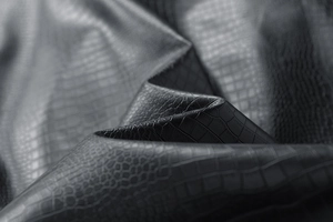 Detailed close-up of premium black crocodile pattern embossed leather with glossy finish