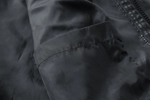 Close-up of black work jacket showing inner pocket structure and precise stitching detail