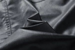 Detailed macro view of the black faux leather jacket texture and high-quality stitching detail