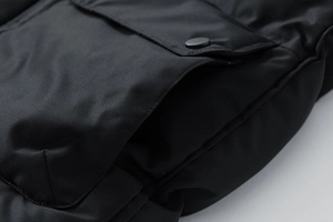 Dettaglio del gilet invernale nero da uomo che mostra il tessuto antivento e la tasca con bottone
