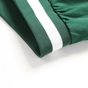 Gros plan du poignet en maille côtelée vert foncé avec rayure blanche sur veste baseball