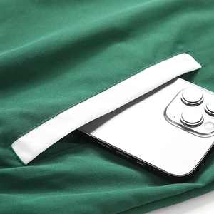 Détail de la poche de veste verte avec bordure blanche montrant sa grande capacité