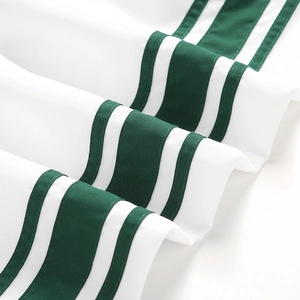 Gros plan sur un tissu textile blanc avec doubles bandes vertes et coutures soignées
