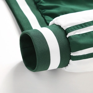 Détail des poignets côtelés verts et des rayures sur la manche d'un blouson baseball