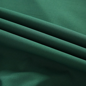 Gros plan du tissu tissé vert foncé montrant la texture douce et les fibres de polyester
