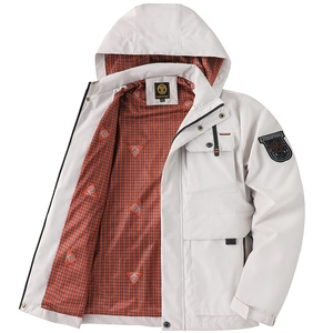 Détail d'une veste blanche à capuche avec doublure à carreaux orange et écusson de bras