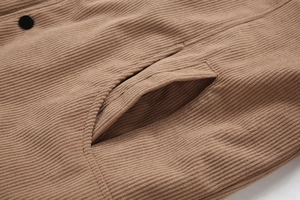 Detailansicht aus nächster Nähe der braunen Cordjacke mit vertikalen Rippen und Taschenknopf