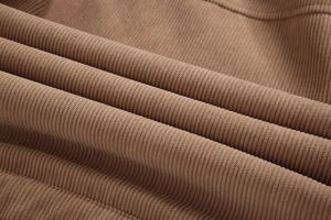 Makroaufnahme der dunkelbraunen Cordstoff-Textur und der weichen Rippenstruktur der Jacke