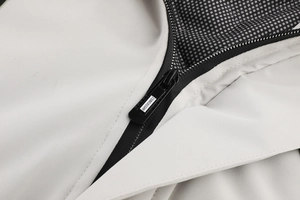 Dettaglio della cerniera premium con logo del marchio su una giacca invernale beige