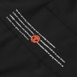 Détail des slogans imprimés et du graphisme orange sur le tissu noir de la veste décontractée