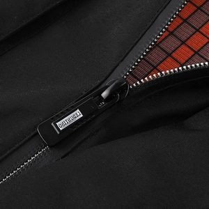 Détail macro du tissu noir de la veste avec doublure à carreaux rouges et fermeture éclair