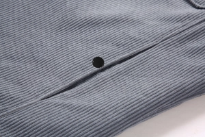 Primer plano detallado de chaqueta de pana gris con textura acanalada y botón negro