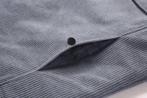 Primer plano de tela de pana azul grisáceo con botón de presión de metal negro mate