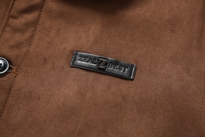 Détail d'une veste en daim marron avec écusson en cuir et garnitures métalliques
