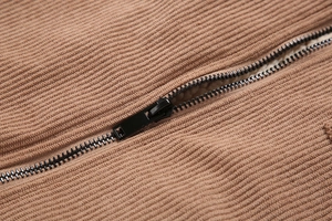 Detailaufnahme der braunen Cordjacke mit schwarzem Metallreißverschluss und warmem Fleecefutter