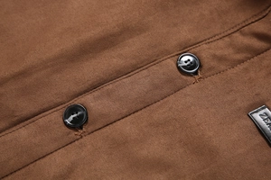 Détail de la veste en daim marron montrant la texture du tissu, boutons et étiquette en cuir