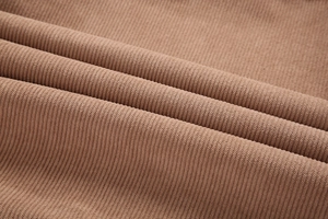 Detailaufnahme der weichen, gestreiften Textur des braunen Cordstoffs einer Herrenjacke
