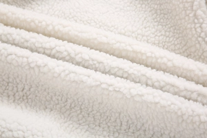 Detalle macro de la suave tela sherpa blanca con textura rizada gruesa y muy esponjosa