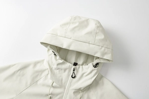 Detail der beigen Outdoor-Jacke mit winddichter Kapuze und hohem Kragen mit Reißverschluss