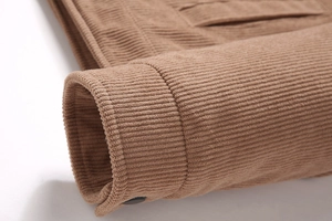 Detailaufnahme der braunen Cordjacke am Ärmel mit Doppelnaht und feiner Textur der Baumwolle