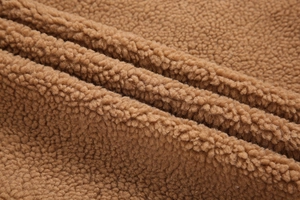 Gros plan sur la doublure épaisse en laine de mouton camel montrant une texture douce