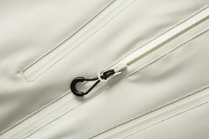 Detailaufnahme des wasserdichten Reißverschlusses einer cremefarbenen Outdoor-Wanderjacke