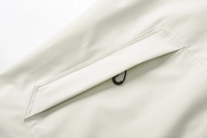 Detail der winddichten Kunstfaser mit Reißverschlusstasche an grauer Outdoor-Jacke