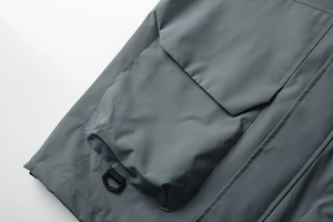 Detail of outdoor jacket showing windproof fabric with large pleated pocket and D-ring buckle