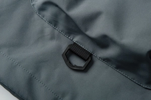 Close-up of durable D-ring buckle and reinforced stitching on gray-blue outdoor jacket