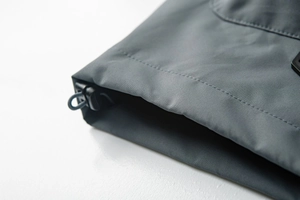 Macro detail of the outdoor jacket hem showing the black adjustable drawstring and stitching