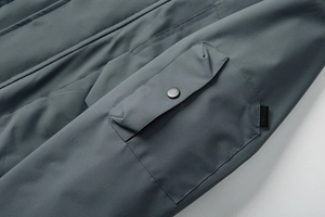 Detail of cargo pocket with matte metal snap and utility loop on outdoor jacket