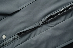 Close-up of windproof jacket with smooth zipper, puller, and metal snap button details