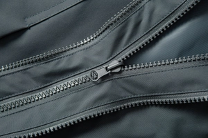 Detail shot of the zipper and high-density synthetic fabric on a blue outdoor jacket