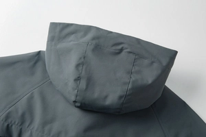 Detail of hood structure and shoulder stitching on a windproof grey-blue outdoor jacket