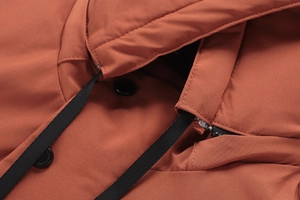 Dettaglio del collo del parka invernale con coulisse nera e bottoni opachi su tessuto arancio