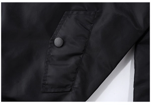 Detail view of the black flight jacket showing a buttoned flap pocket and smooth fabric
